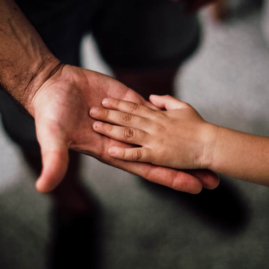 kids hand resting in man's hand